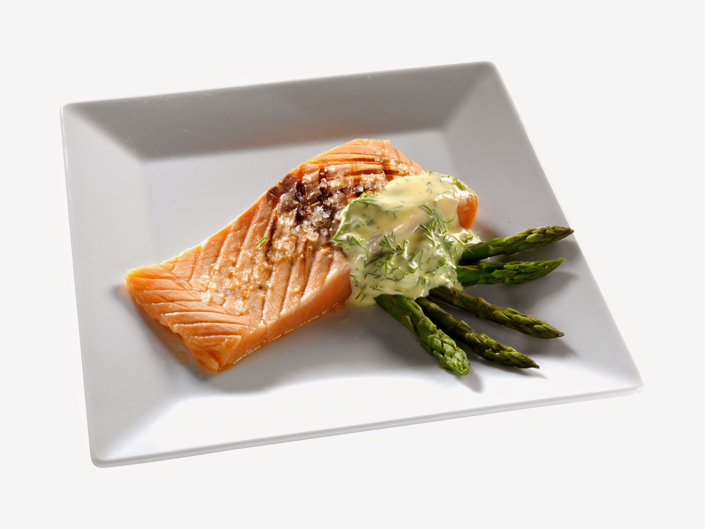 A seared salmon portion with sauce and green asparagus on a white plate.